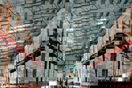 Rows of shelves partially filled with boxes of manufactured goods in a trading company's warehouse