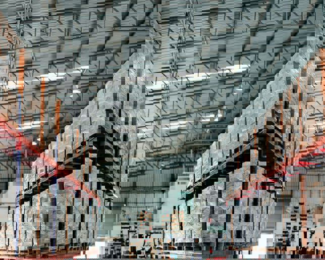 Rows of shelves partially filled with boxes of manufactured goods in a trading company's warehouse
