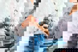 A woman performs wrist and arm exercises with a hand weight, guided by a female occupational therapist.