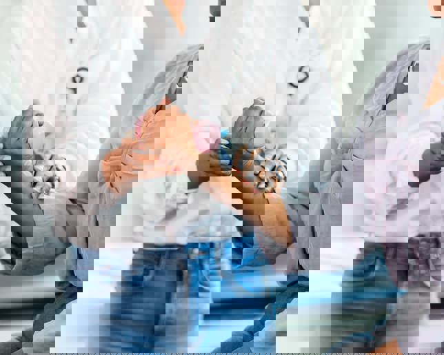 A woman performs wrist and arm exercises with a hand weight, guided by a female occupational therapist.