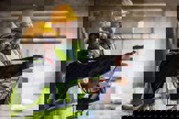 Architects using digital tablet and discussing at the construction site