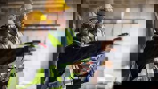 Architects using digital tablet and discussing at the construction site