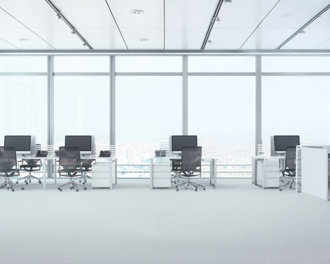 Bright open-plan office with four desks, monitors, and rolling chairs beside floor-to-ceiling windows