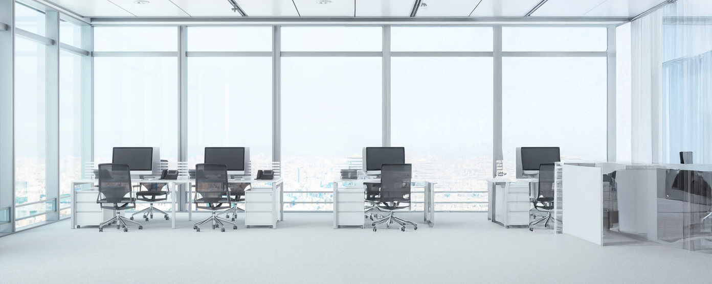 Bright open-plan office with four desks, monitors, and rolling chairs beside floor-to-ceiling windows
