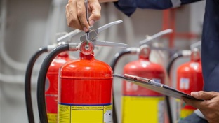 Close up of a hand holding a red fire extinguisher