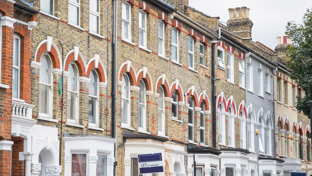 Row of traditional brick terraced houses in the UK with "LET" and "FOR SALE" signs, indicating properties on the market.