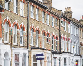Row of traditional brick terraced houses in the UK with "LET" and "FOR SALE" signs, indicating properties on the market.