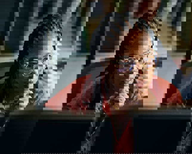 Young woman programmer focused on her work, coding on dual monitors in a modern office environment