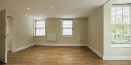 Empty room with wooden floor and two windows.