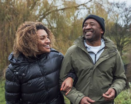 a couple happily walking along arm in arm in nature