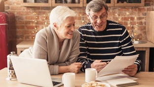 A smiling mature couple looking at paperwork in the kitchen