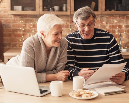 A smiling mature couple looking at paperwork in the kitchen