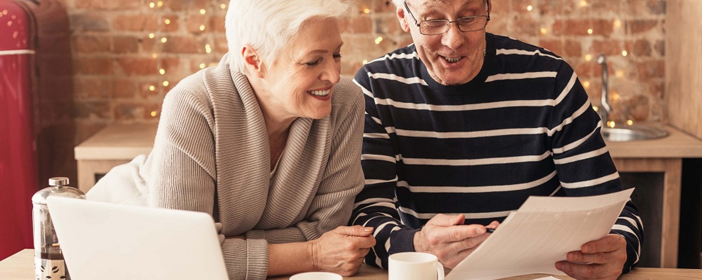 A smiling mature couple looking at paperwork in the kitchen