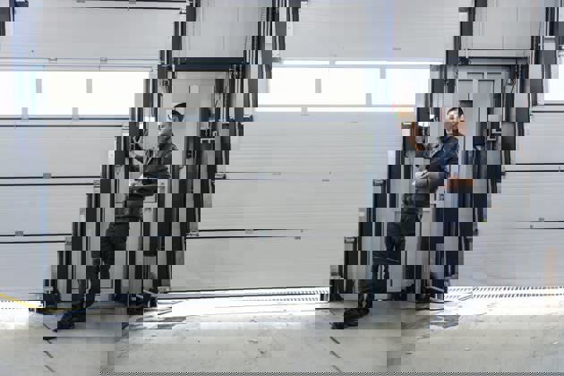 A mechanic is pressing button and opening garage door at the car workshop.