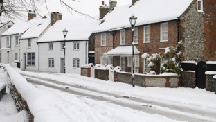Snow-covered village street with houses.