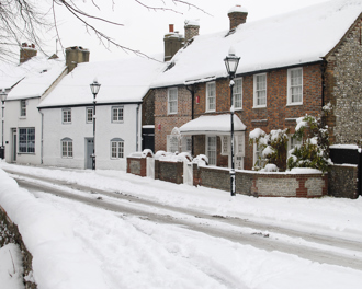 Snow-covered village street with houses.