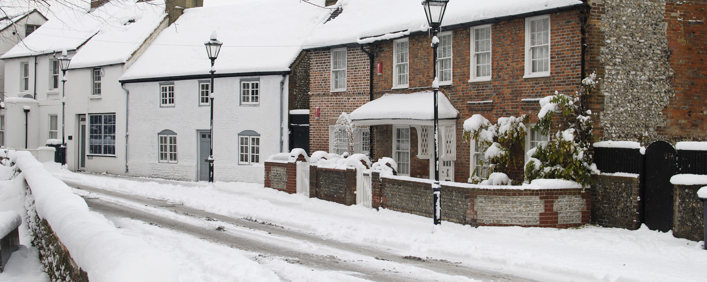Snow-covered village street with houses.