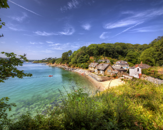 Stone cottages along a small sandy beach, surrounded by lush green hills
