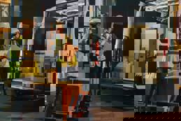 Distributors manager talks to a worker loading a delivery truck with cardboard boxes of online orders.