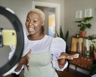 Content creator recording video with phone and ring light.