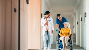 Carer wheeling lady along corridor in a wheelchair