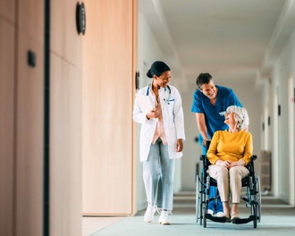 Carer wheeling lady along corridor in a wheelchair