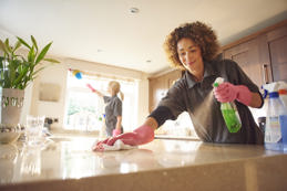 Ttwo professional cleaners in a domestic kitchen spraying cleaner 
