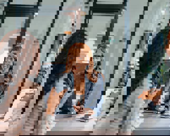 Three business professionals in a modern office meeting discuss a new project, showcasing teamwork and collaboration.