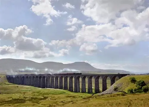  Steam train crossing the Ribblehead Viaduct in the Yorkshire Dales, with rolling hills and wide open moorland under a bright sky.