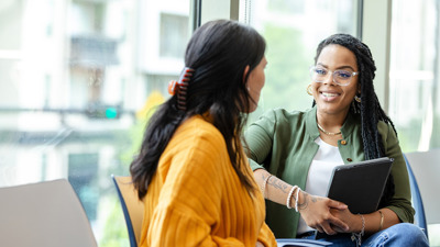 Two seated women talking to one another, one advising the other