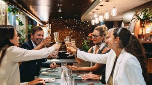 A group of friends clinking champagne flutes in a restaurant