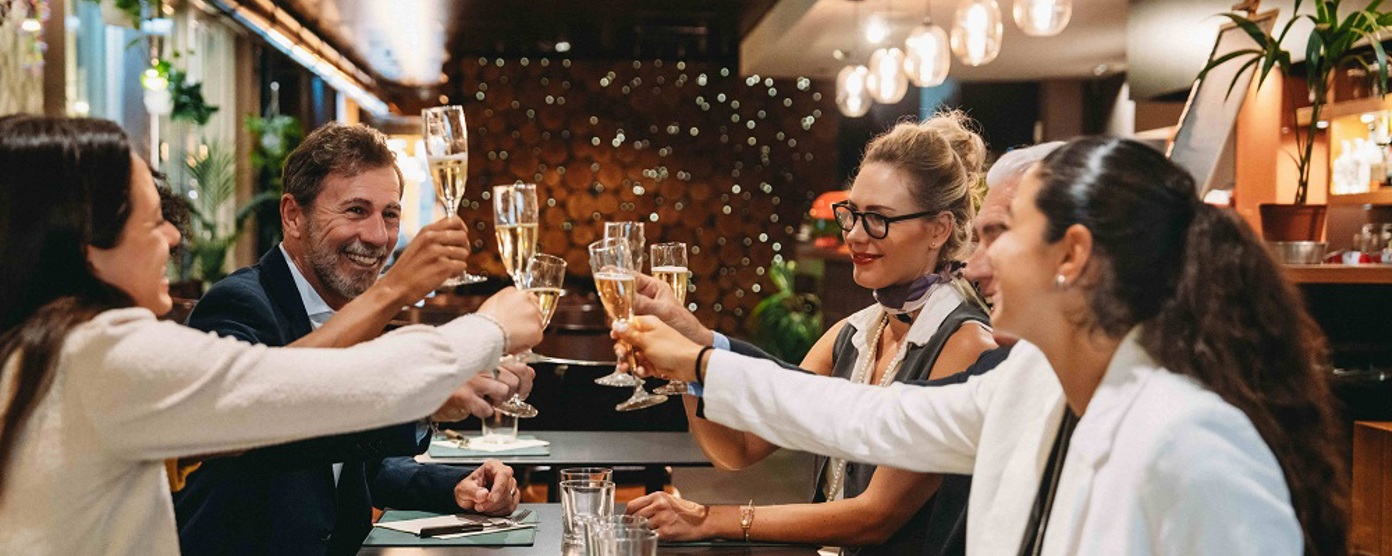 A group of friends clinking champagne flutes in a restaurant