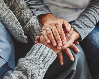 Close up of a carer and patients hands intertwined