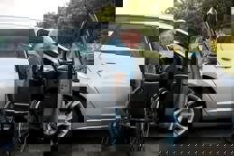 A disabled driver prepares for a day out, moving from his adapted car to his wheelchair on a bright summer morning.