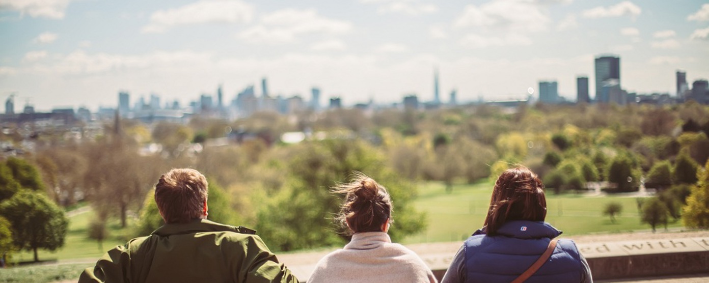 Three people sitting on a bench admiring a view