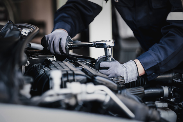 Mechanic working on a vehicle in a garage wearing gloves