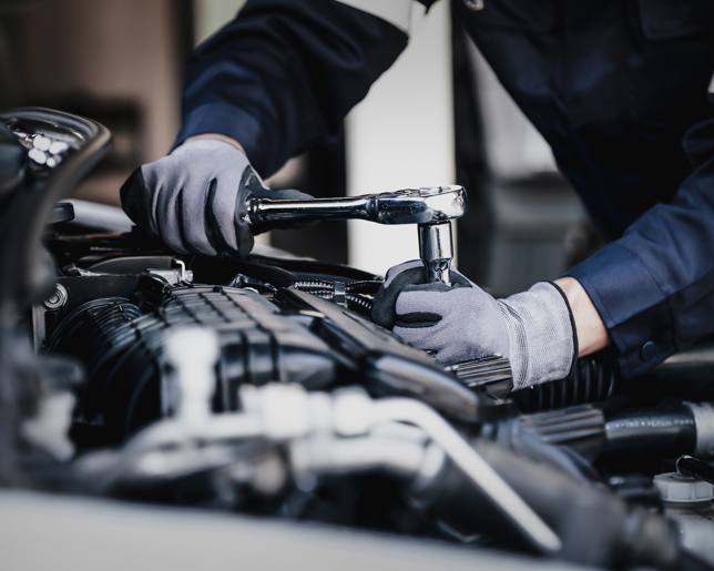 Mechanic working on a vehicle in a garage wearing gloves