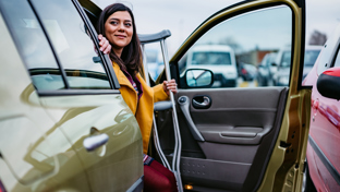 Woman with crutches stepping out of a car in a parking lot, suggesting accessibility and mobility support