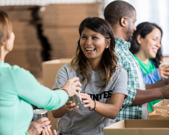 Volunteers joyfully sorting and packing canned goods at a food bank, contributing to a charity event for those in need.