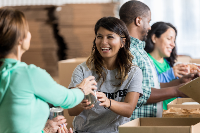 Volunteers joyfully sorting and packing canned goods at a food bank, contributing to a charity event for those in need.