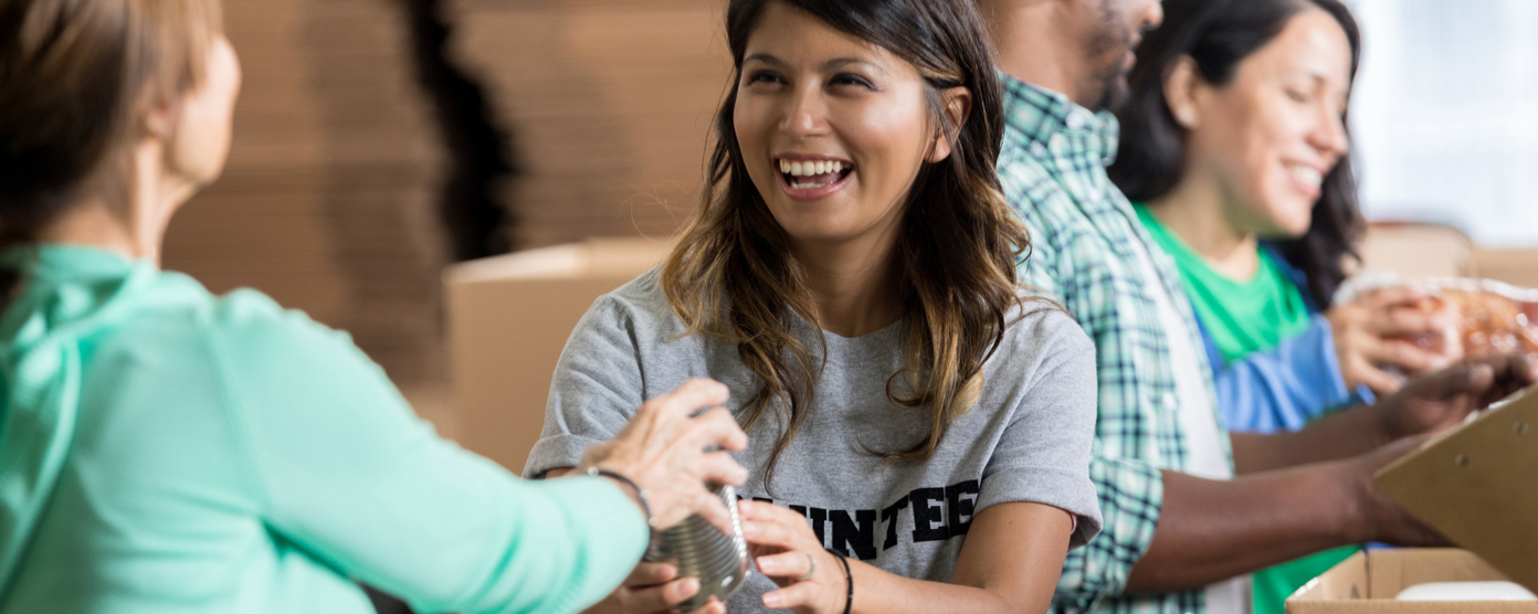 Volunteers joyfully sorting and packing canned goods at a food bank, contributing to a charity event for those in need.