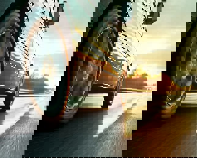 Car rushes along the highway at sunset