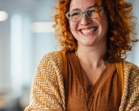 Lady wearing glasses crossing her arms with a big smile on her face