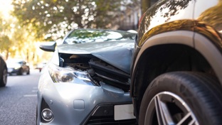 Close up of a car bonnet crushed against another car on a road