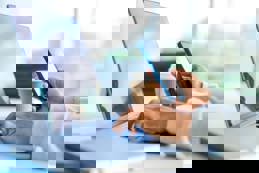 Businessman working on a laptop computer and holding and looking at a mobile phone related to media production