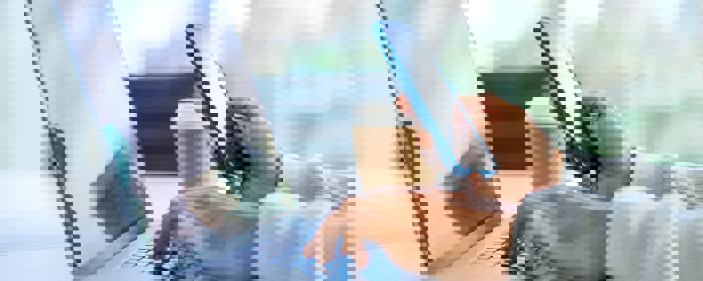 Businessman working on a laptop computer and holding and looking at a mobile phone related to media production