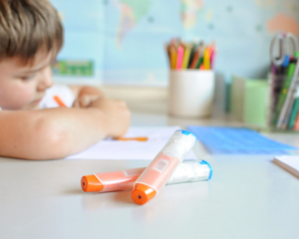 Two epinephrine auto-injectors on a school desk with a child studying in the background, highlighting allergy preparedness
