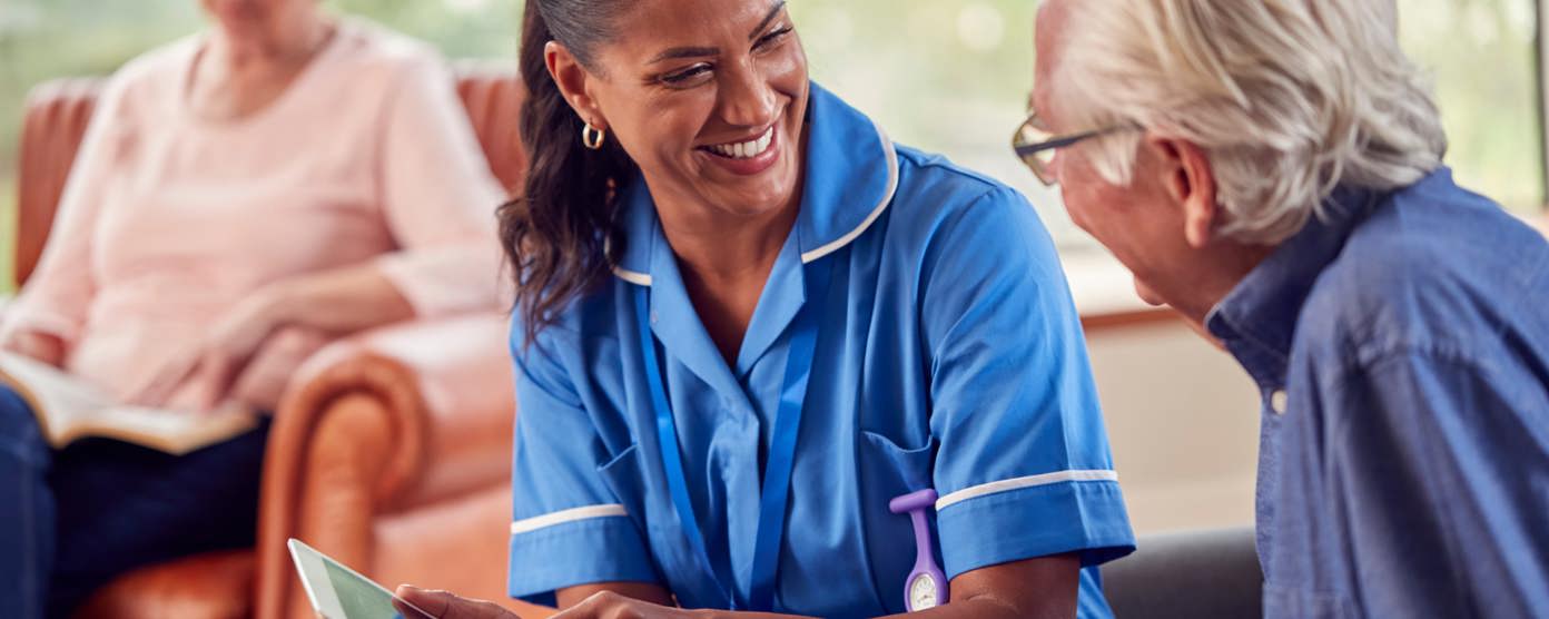 A care worker discussing a care plan on a tablet with an elderly resident at the home.