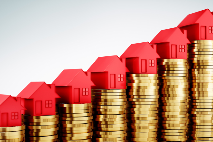 Stacks of golden coins topped with red houses illustrate rising real estate values or investment growth.