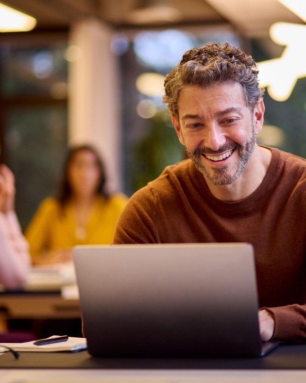 Man smiling using his laptop in aan office